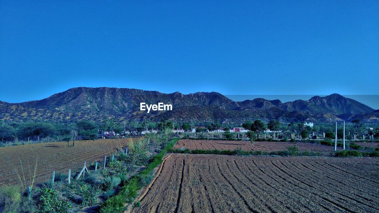 SCENIC VIEW OF FIELD AND MOUNTAINS AGAINST BLUE SKY