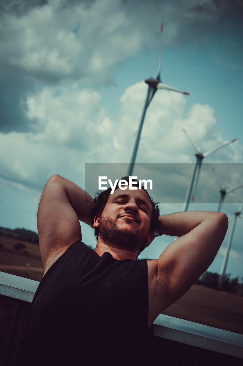 Low angle view of man looking away against sky relaxing and streching