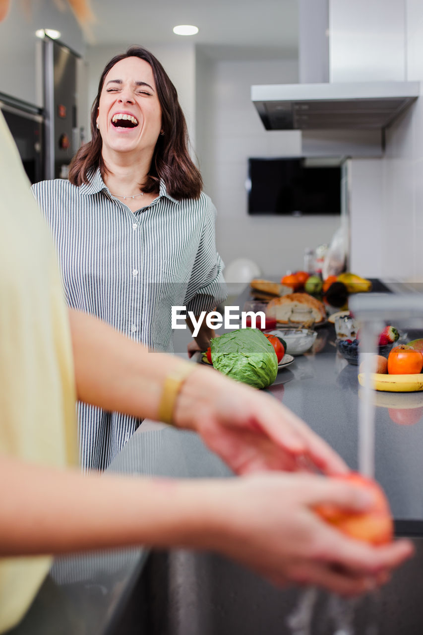 Woman preparing food while standing with friend in kitchen