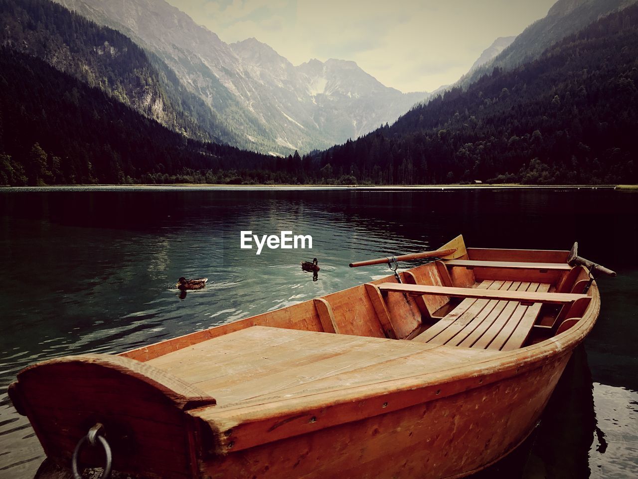 Boats moored in lake against mountains