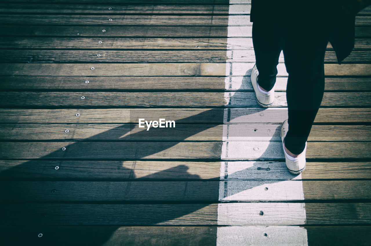 Low section of woman standing on boardwalk