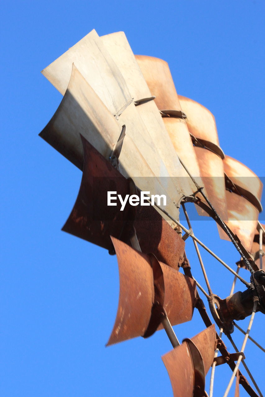 Low angle view of american-style windmill against clear blue sky