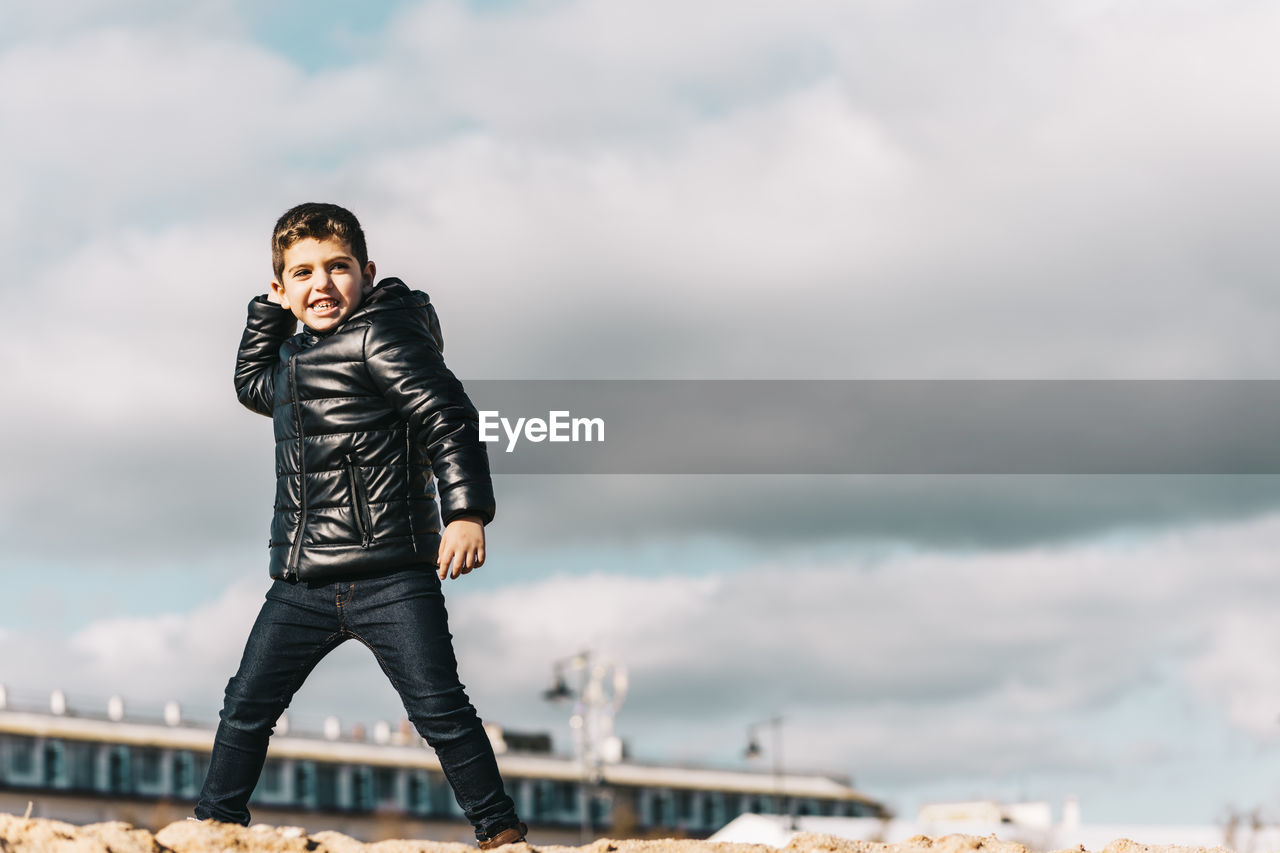 Cute boy standing against sky