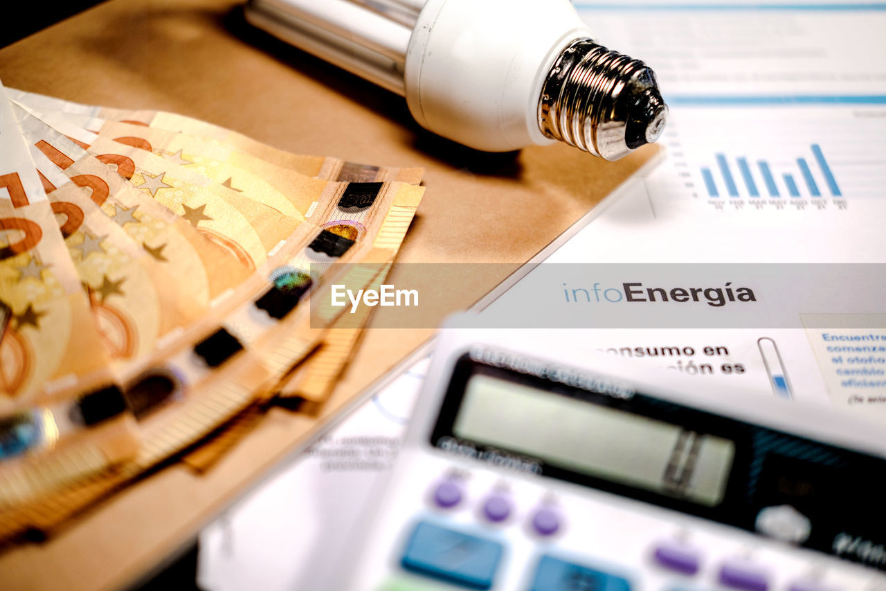 Vertical picture of electricity bill usage in 2022. euro cash money, calculator and light bulb 
