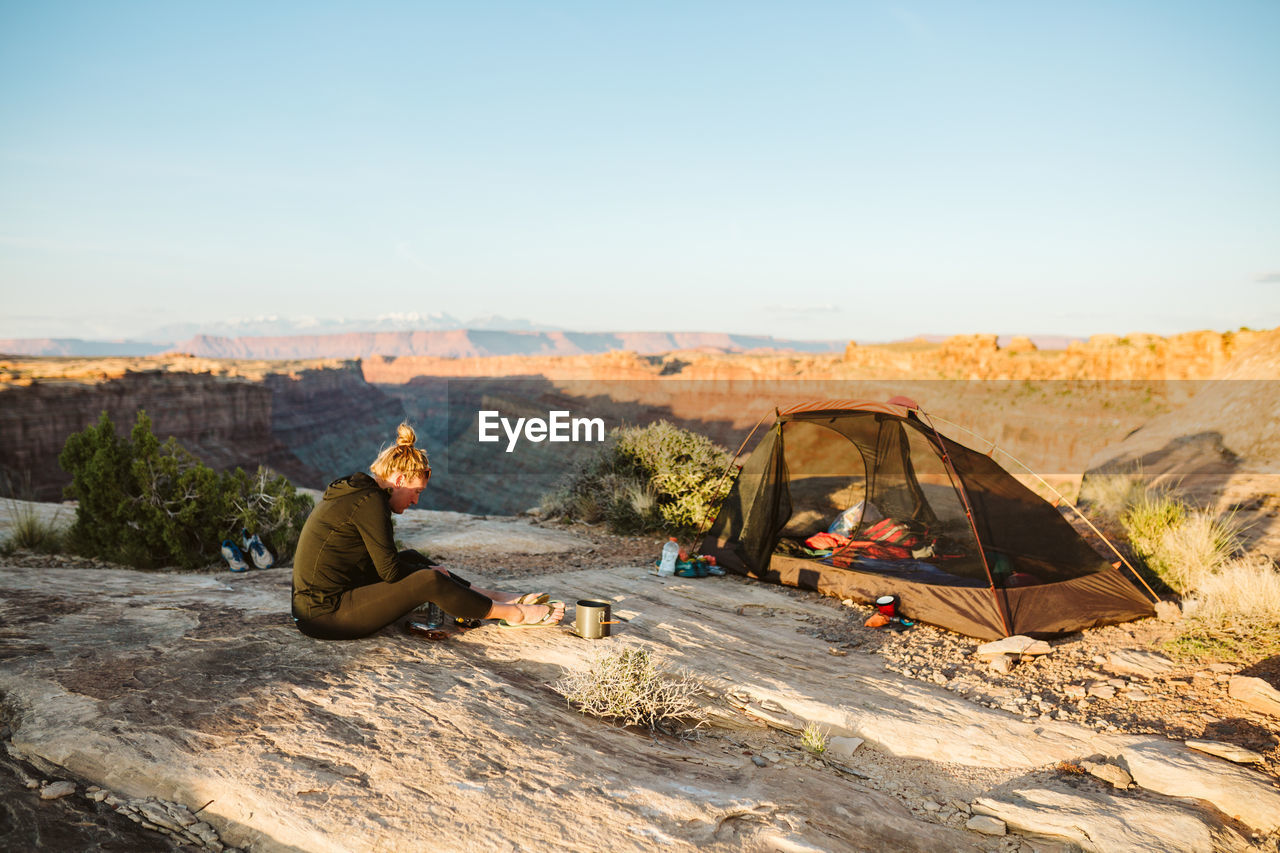 Female camper prepares food next to campsite overlooking grand canyon