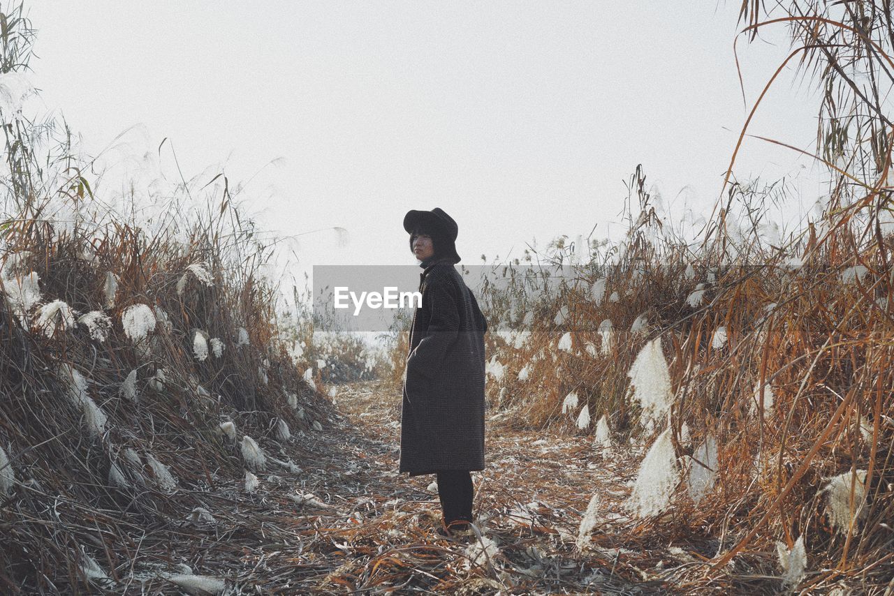 Woman standing on field against clear sky during winter