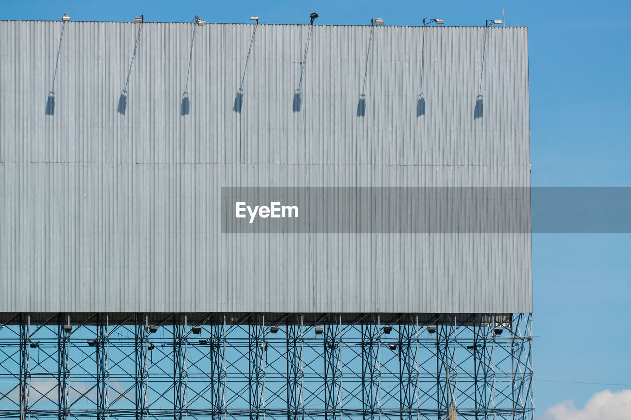 LOW ANGLE VIEW OF METALLIC STRUCTURE AGAINST BUILDING