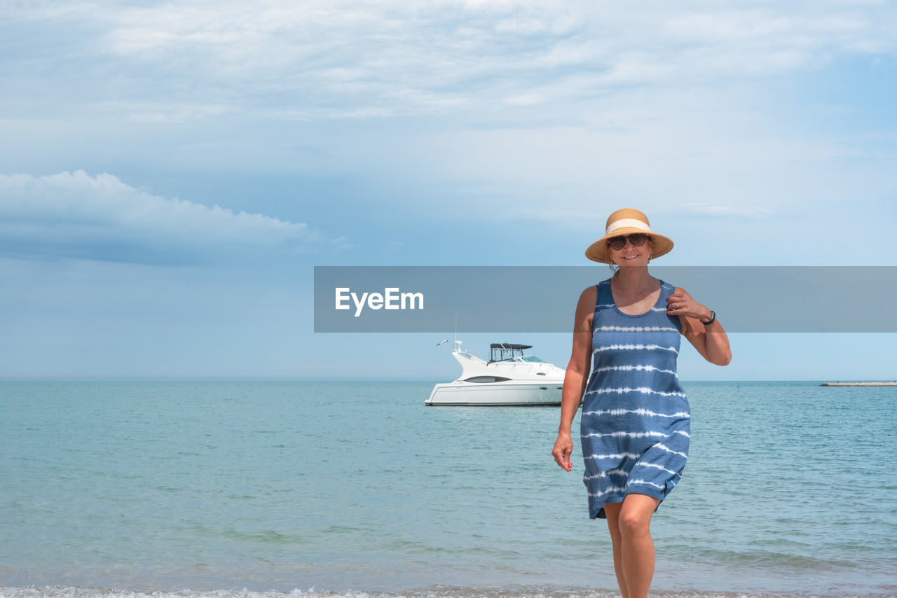 Portrait of woman standing at beach against sky