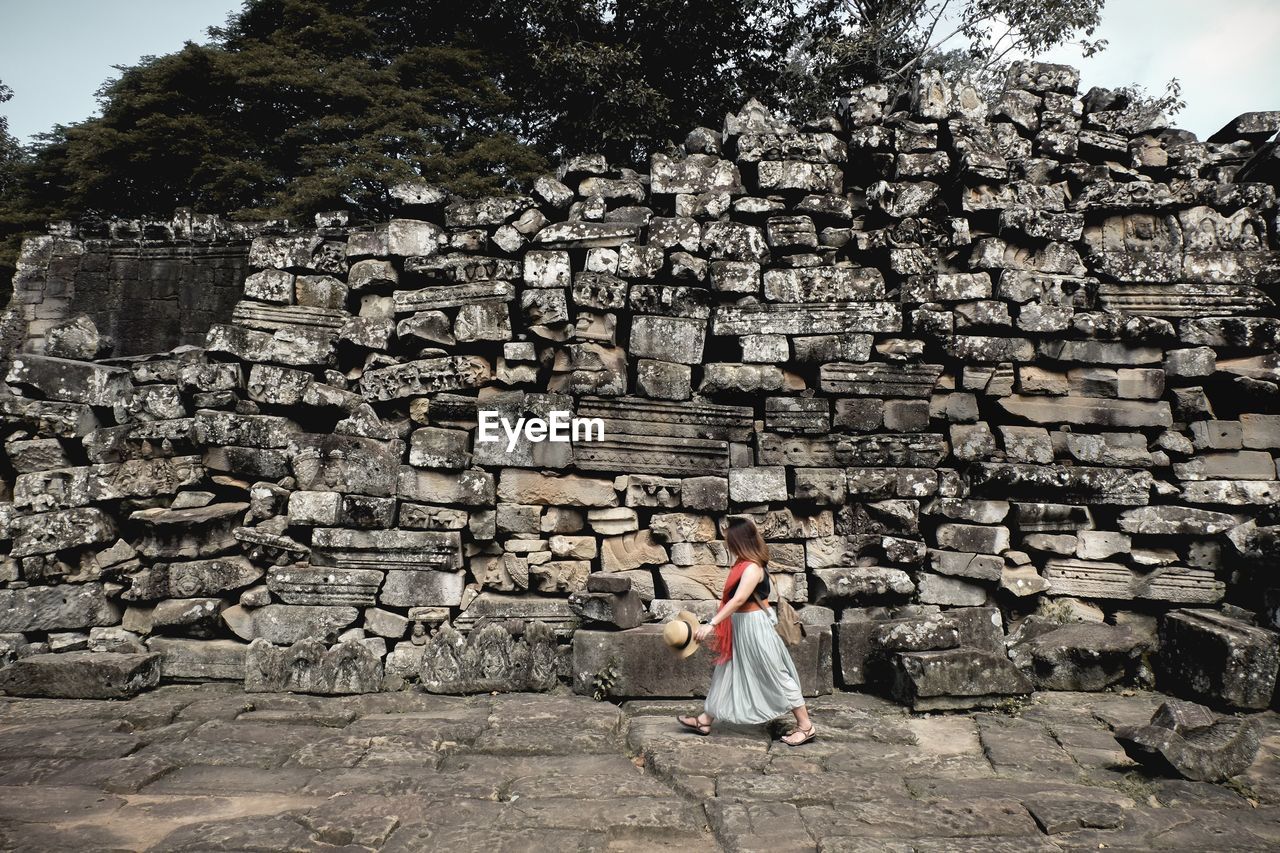 WOMAN STANDING IN FRONT OF OLD RUIN