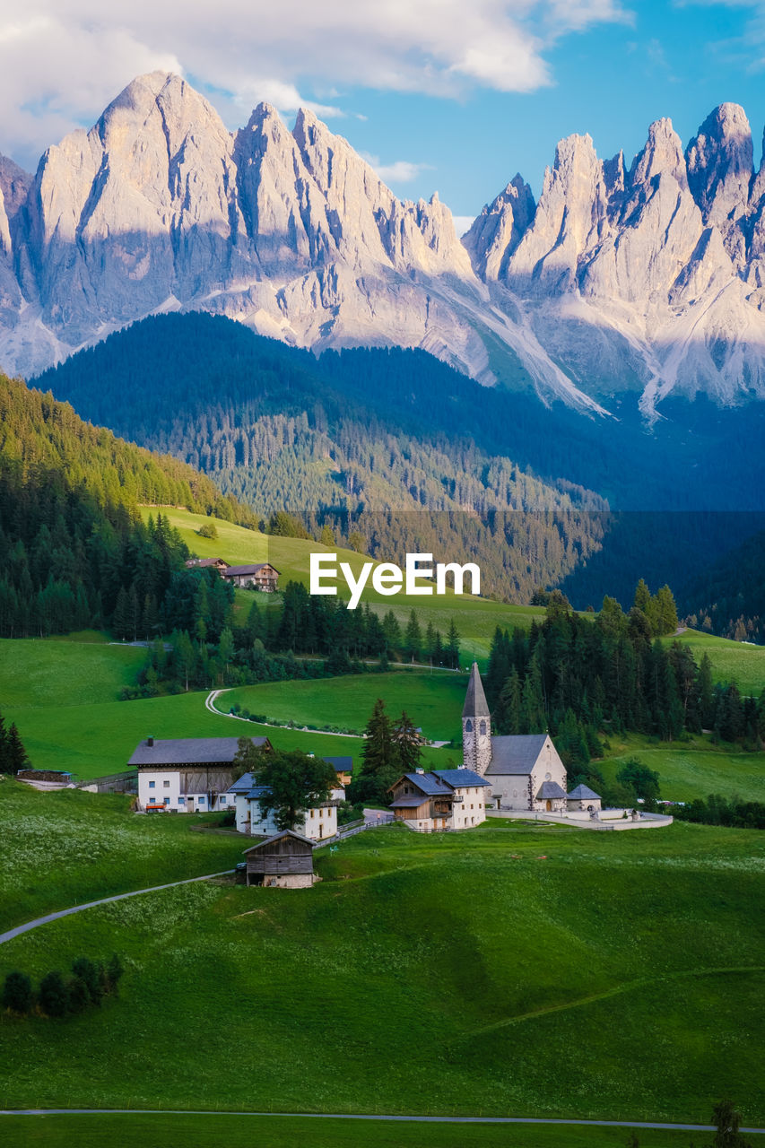 Houses on field by mountains against sky