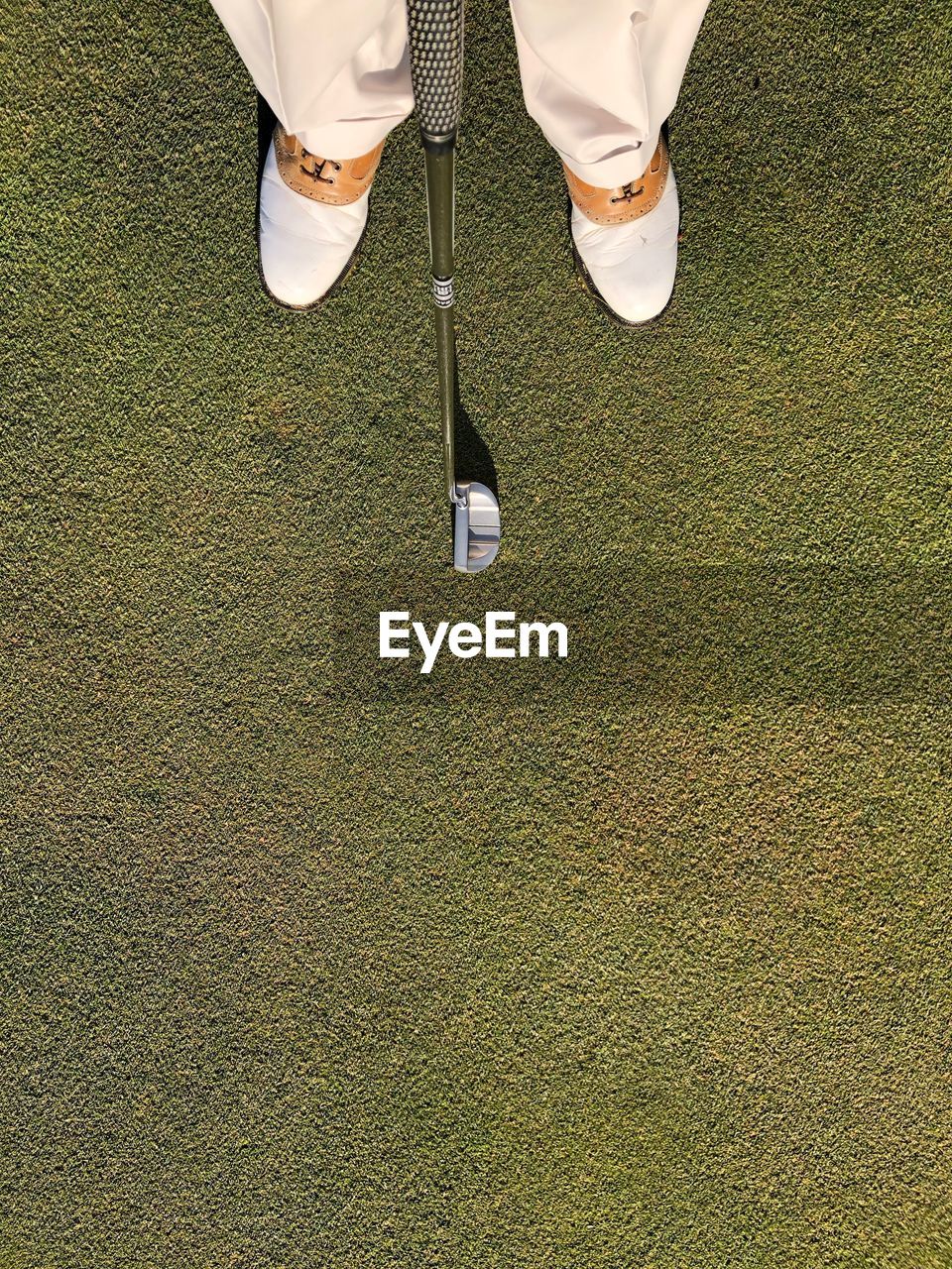 Low section of man with golf club standing on grass