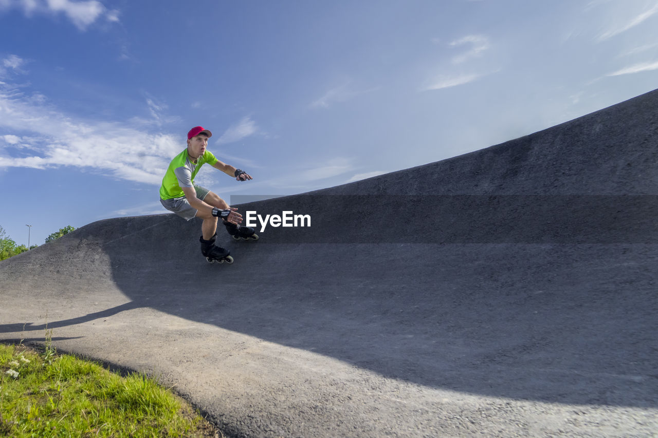 Male athlete skating on pump track during sunny day