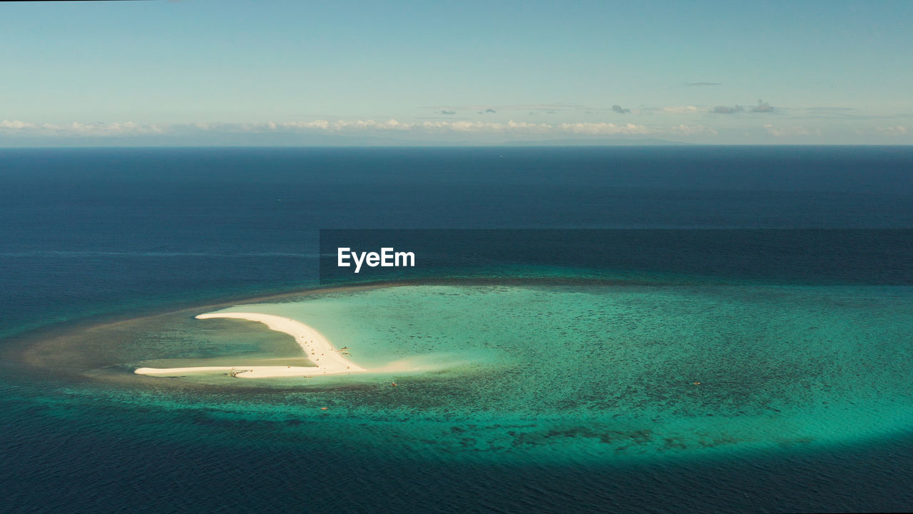 Beautiful beach on tropical island surrounded by coral reef, sandy bar with tourists, top view. 