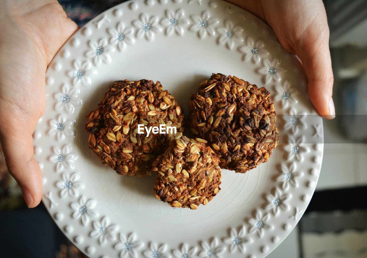 Close-up of hands holding plate of cookies