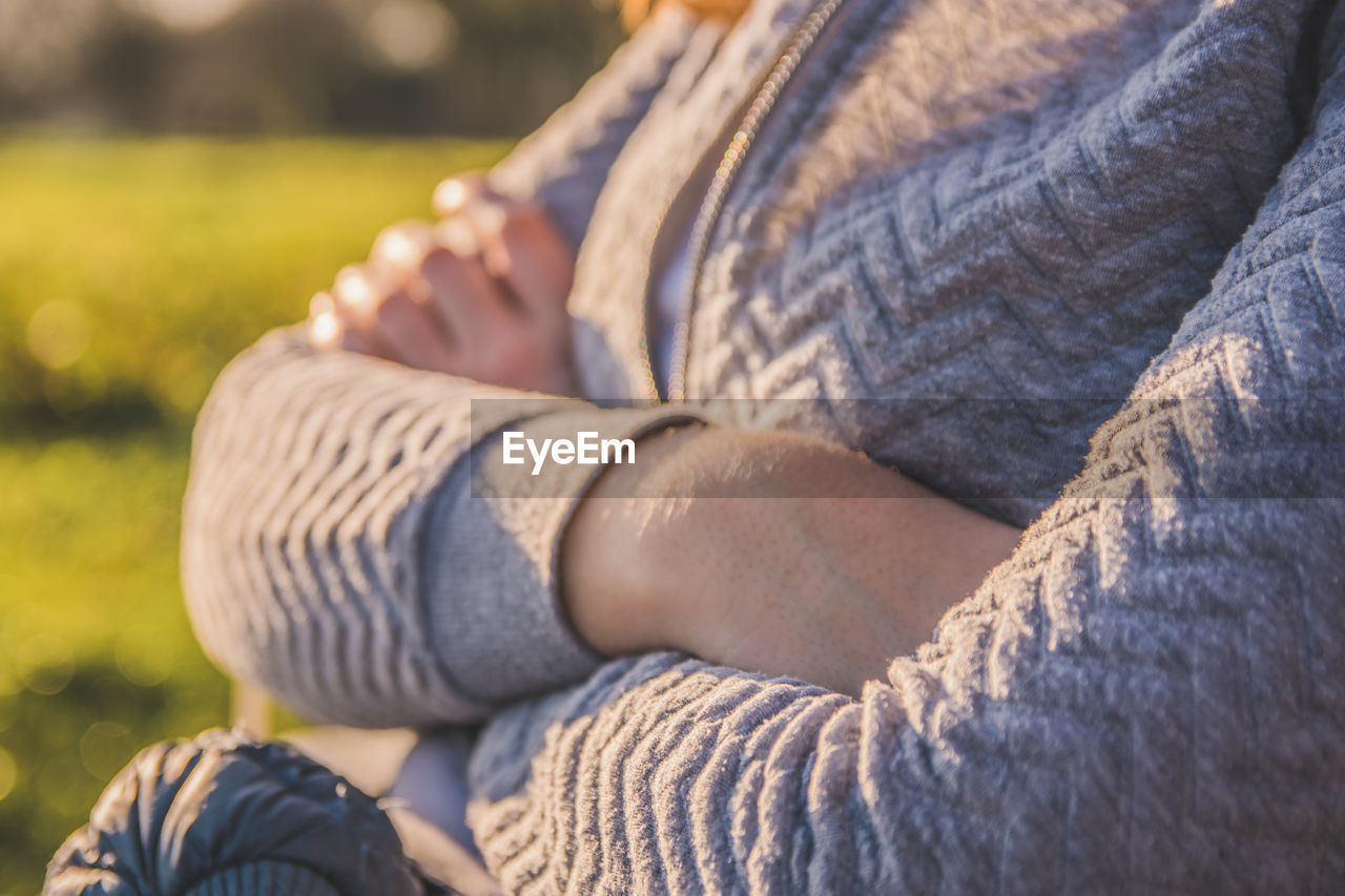 Midsection of woman sitting outdoors