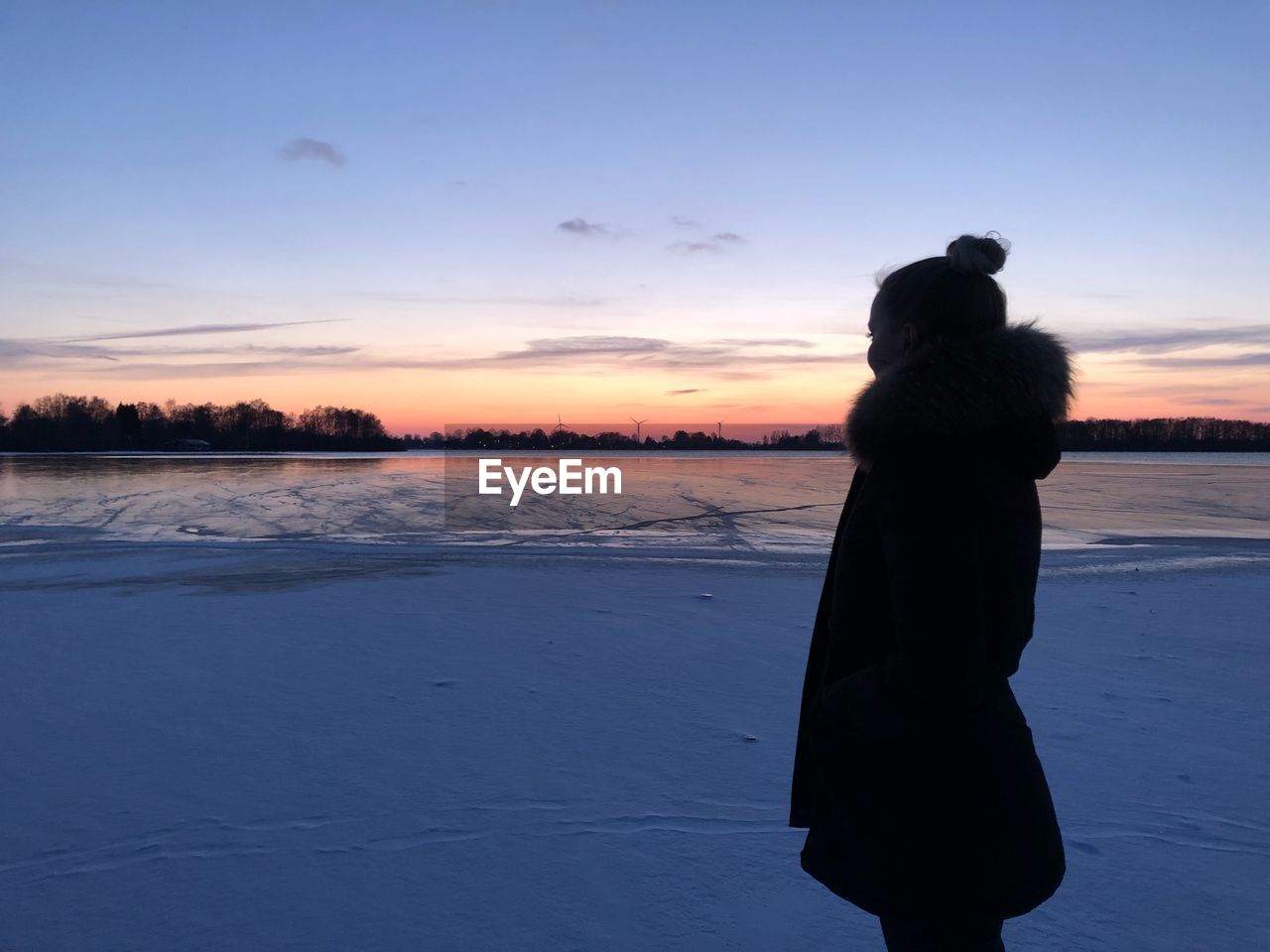 Woman standing on frozen lake against sky