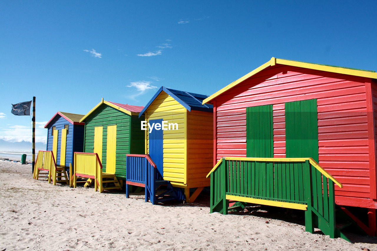 Colorful huts at sandy beach against sky