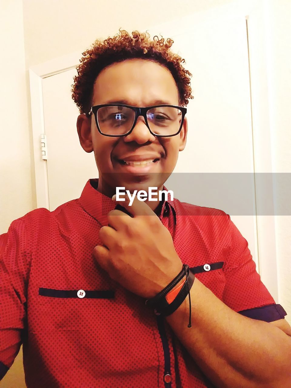 Portrait of smiling mature man wearing eyeglasses and red shirt at home