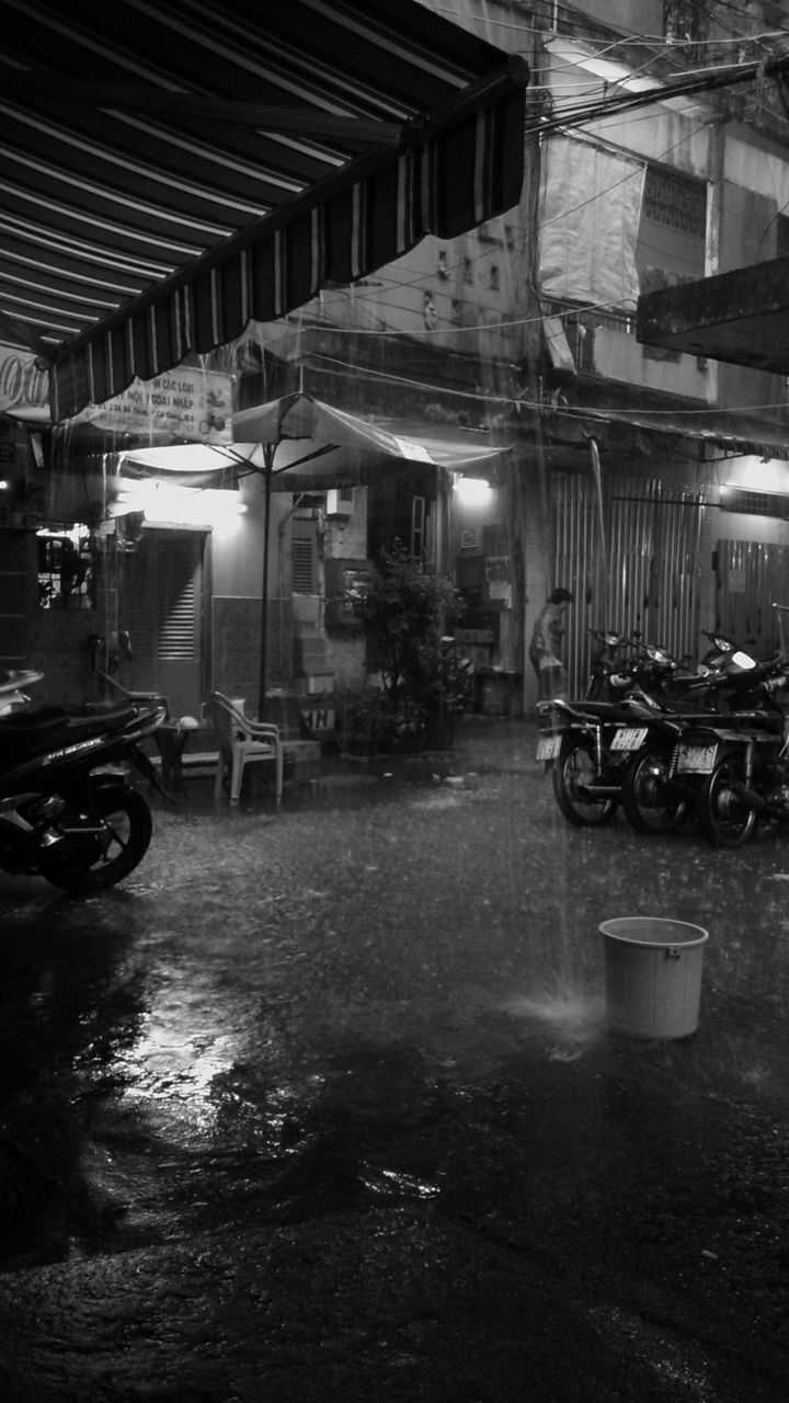 Motorcycles parked by building during rainy season