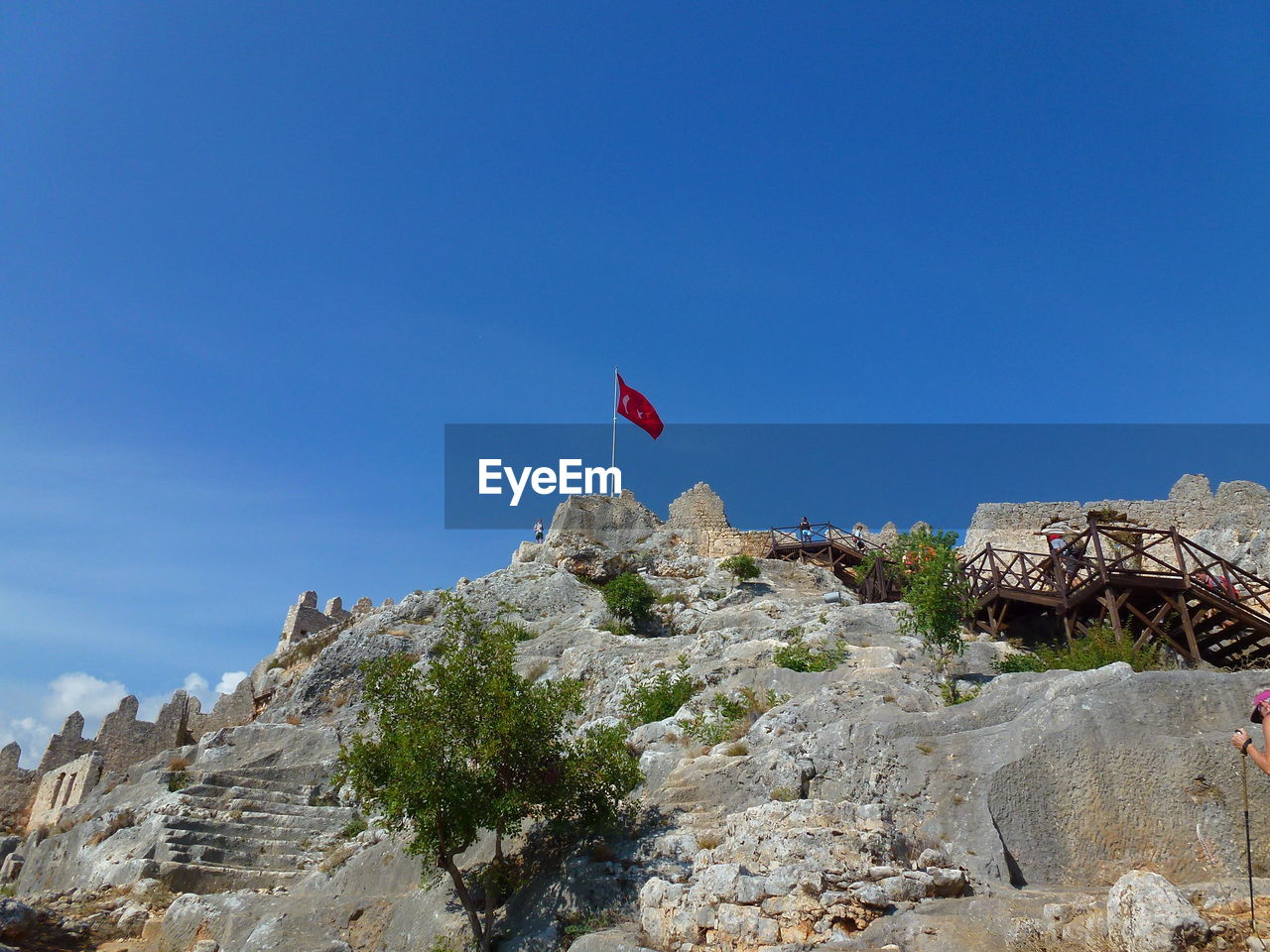 Low angle view of turkish flag on mountain against blue sky