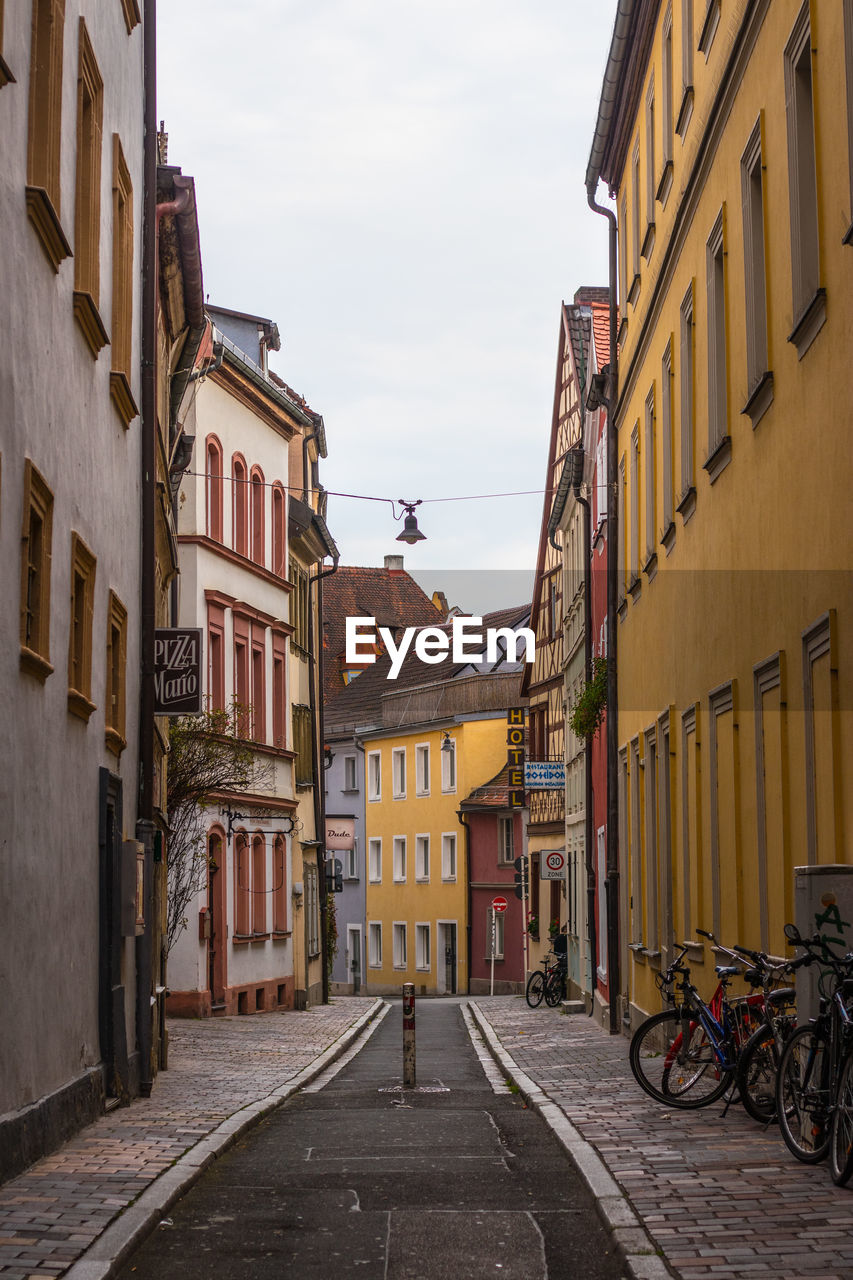 FOOTPATH AMIDST BUILDINGS AGAINST SKY