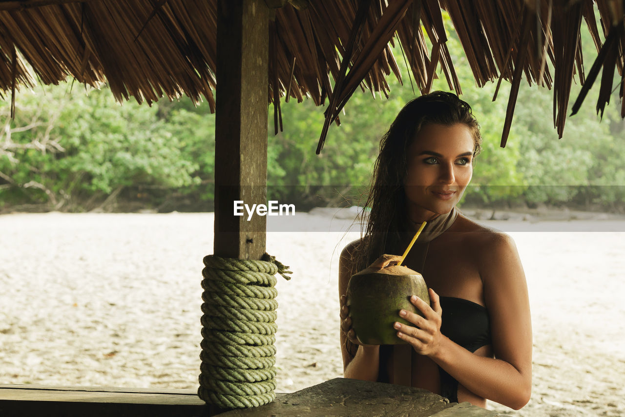 Woman looking away holding coconut water