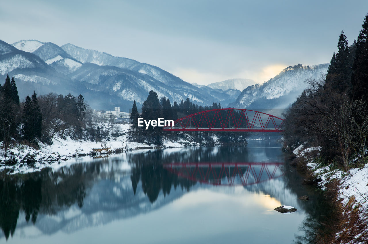 Arch bridge over lake against snowcapped mountains