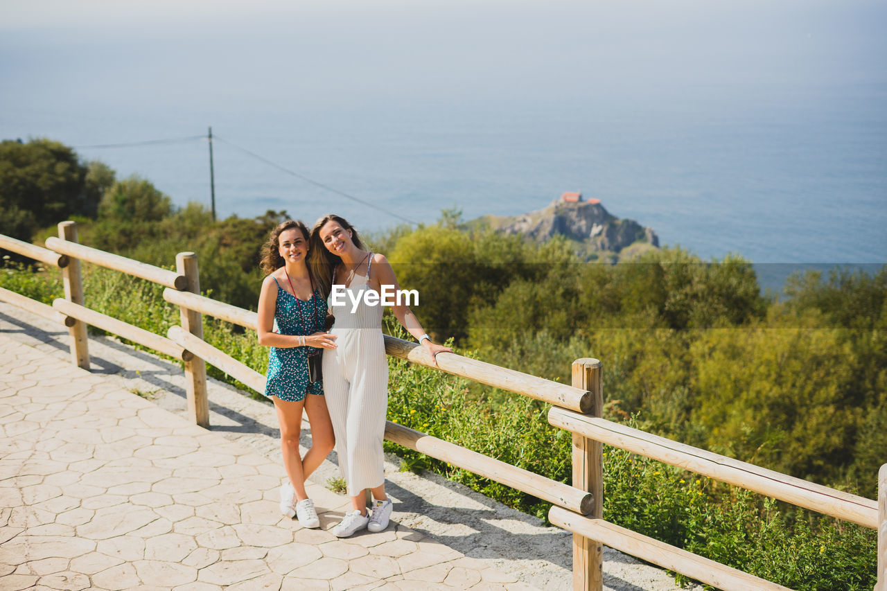 Portrait of women while standing by railing against sea