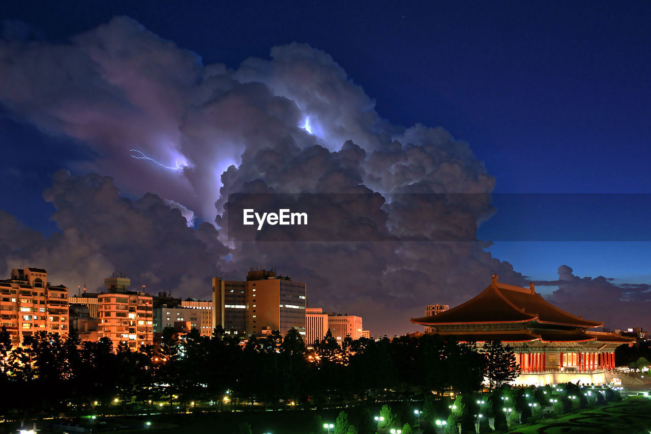 LOW ANGLE VIEW OF ILLUMINATED CITY AGAINST SKY