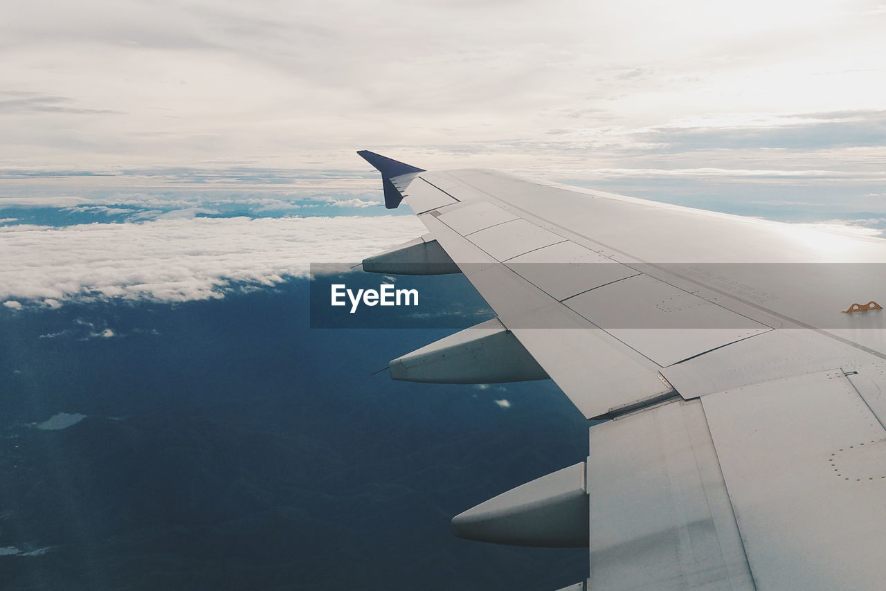 CLOSE-UP OF AIRPLANE WING OVER CLOUDS