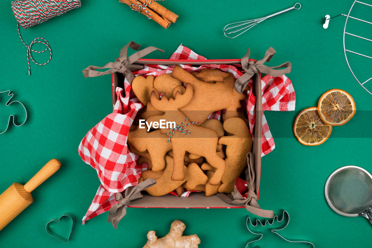 Top view of freshly backed christmas gingerbread cookies on red plaid napkin, fresh ginger, cinnamon