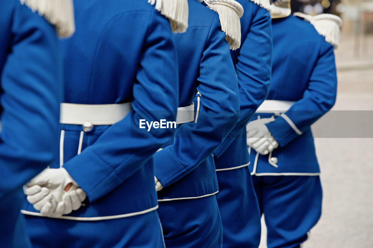 Rear view of people standing on street in blue uniform