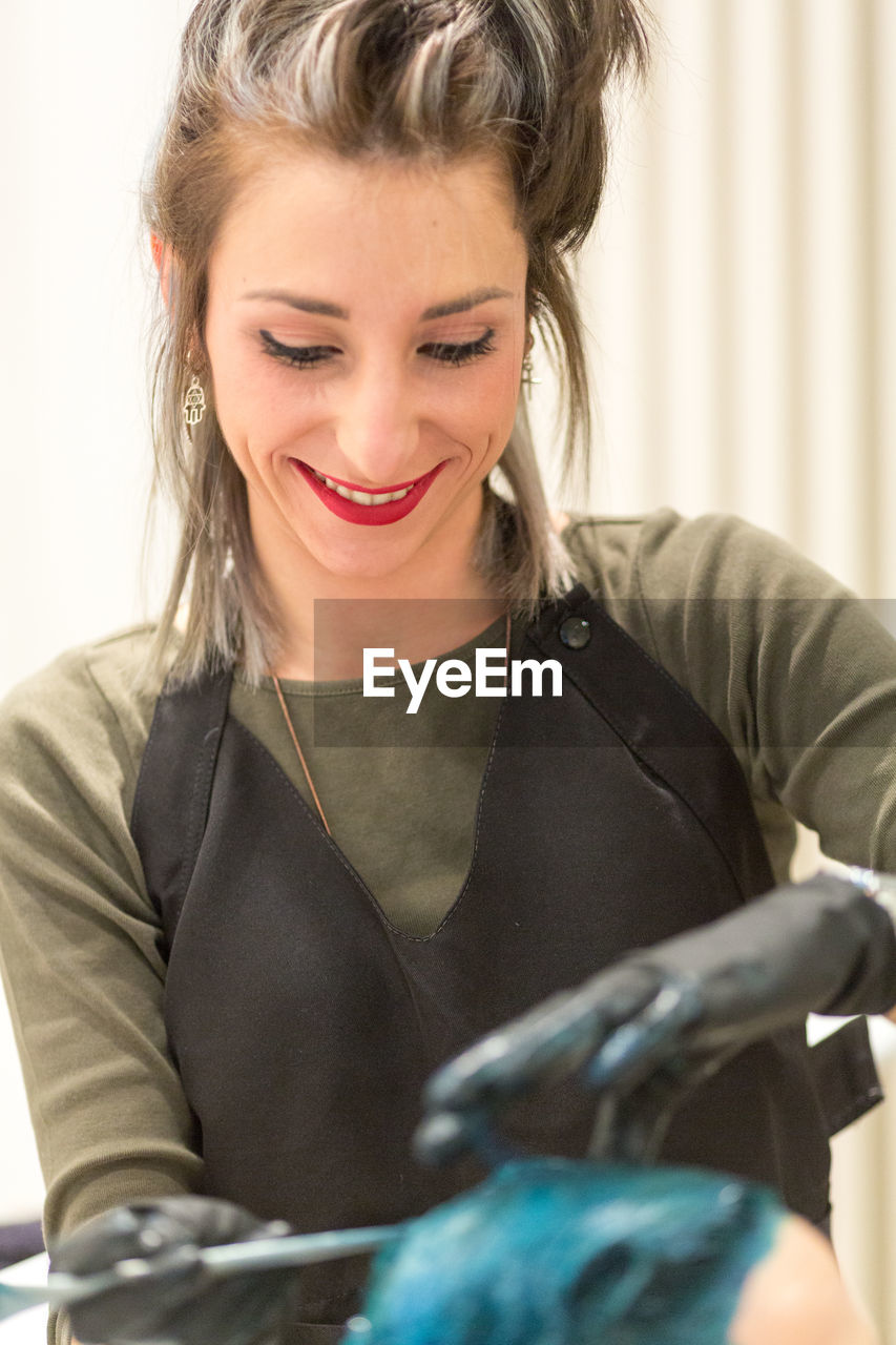 Smiling young woman dying customer hair at salon