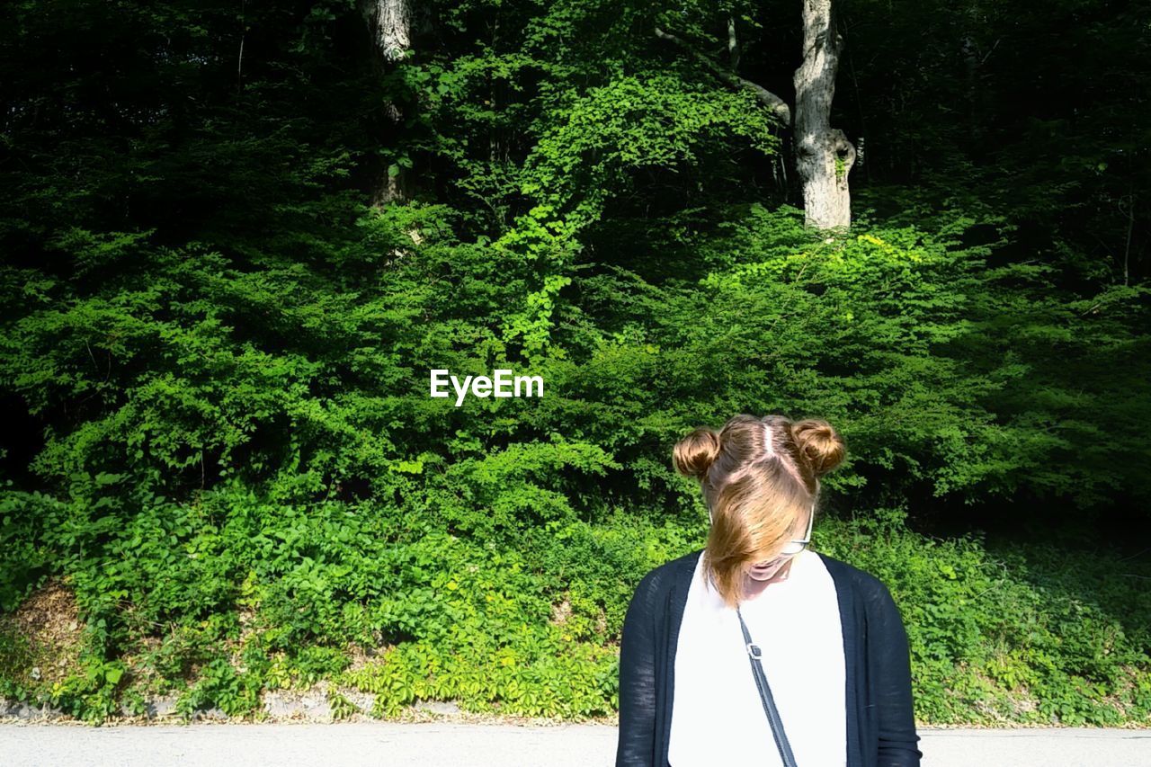 Young woman standing against trees