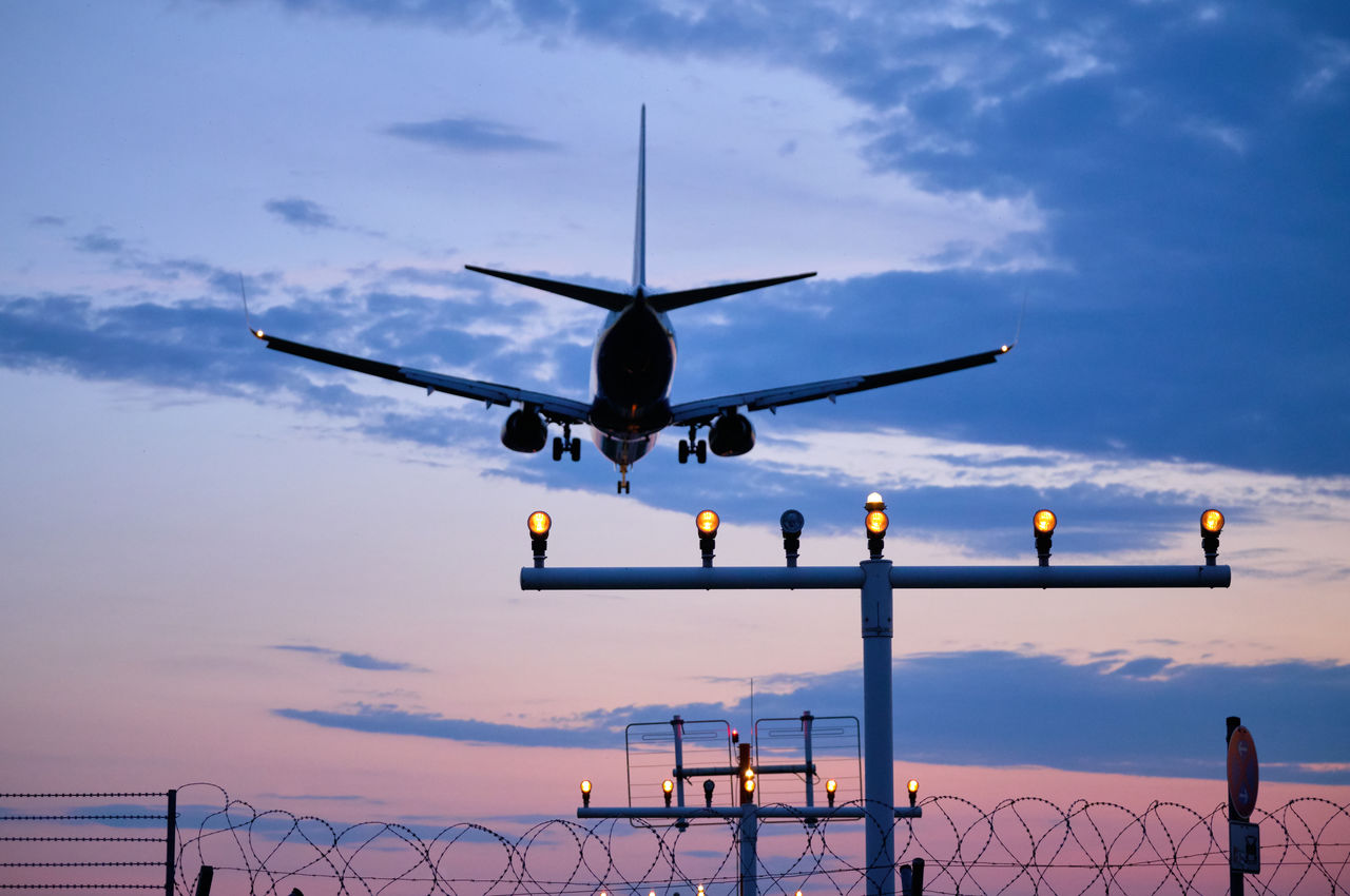 LOW ANGLE VIEW OF AIRPLANE FLYING IN SKY DURING SUNSET