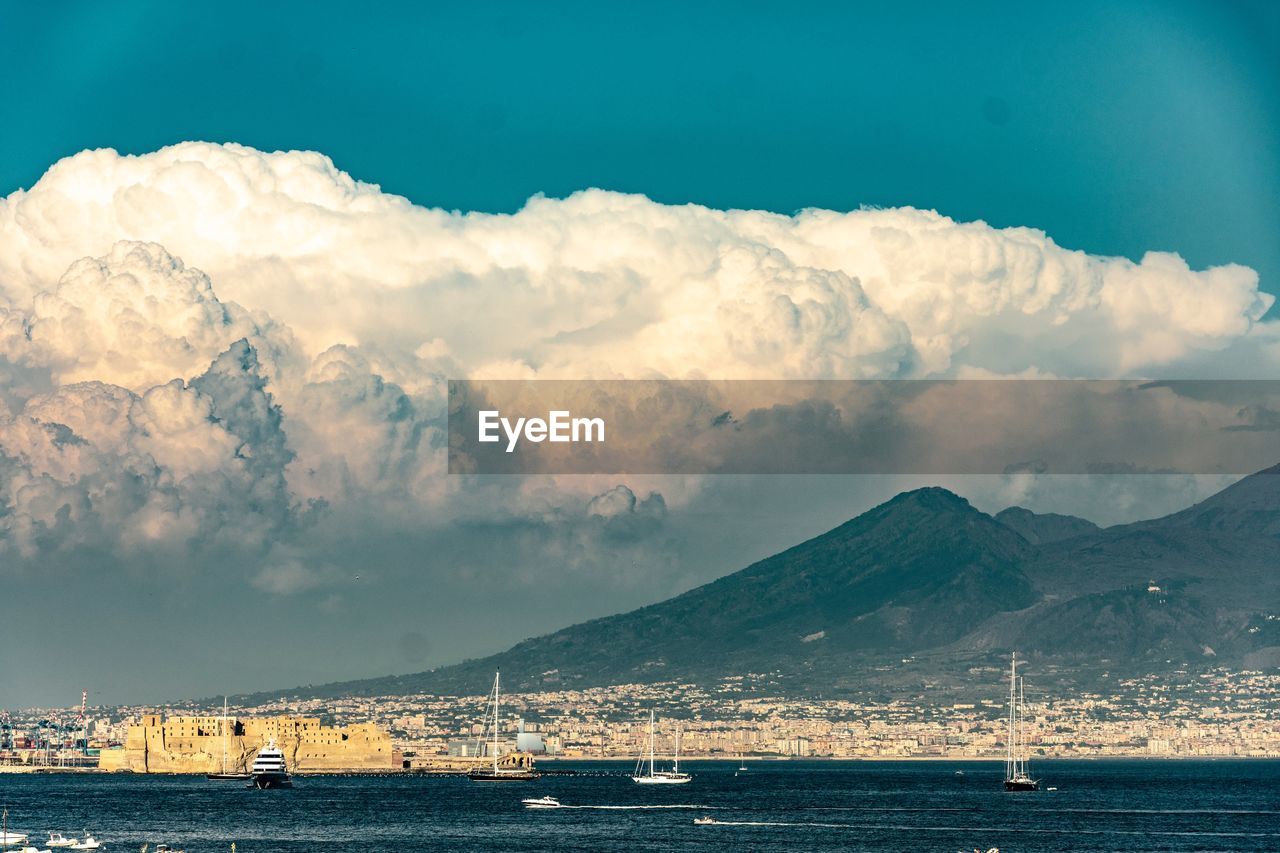 Scenic view of sea by mountains against sky