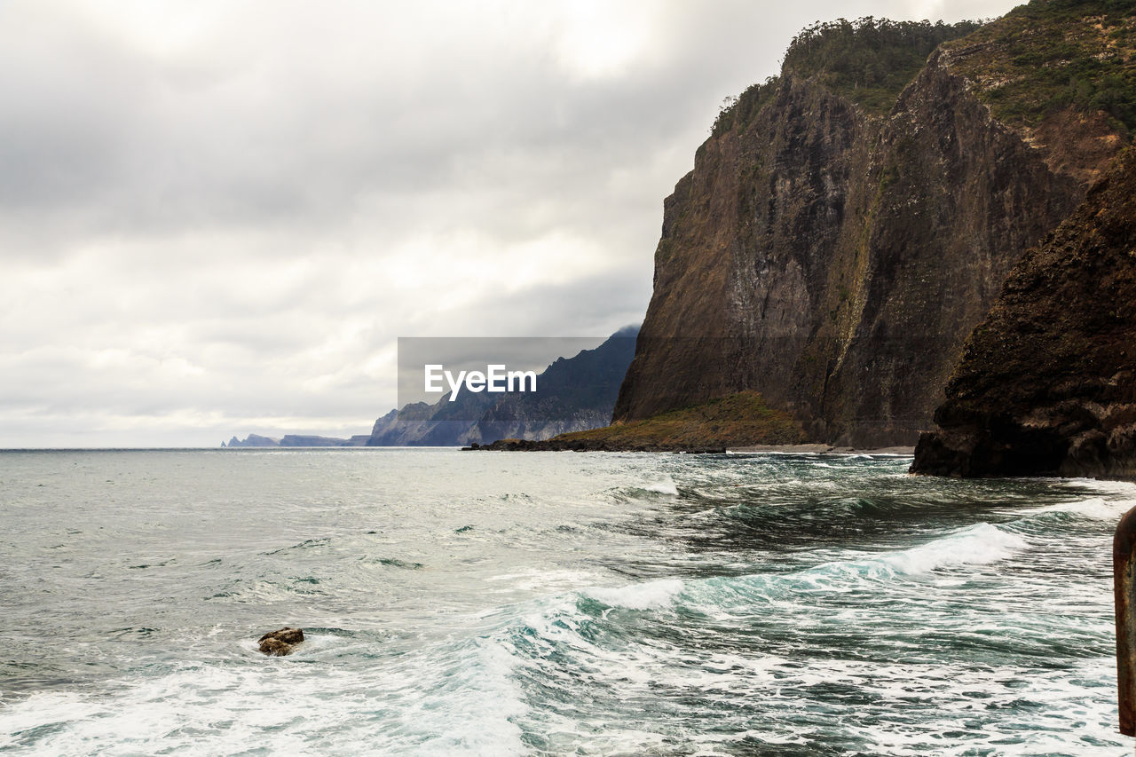 Scenic view of sea and mountains against cloudy sky