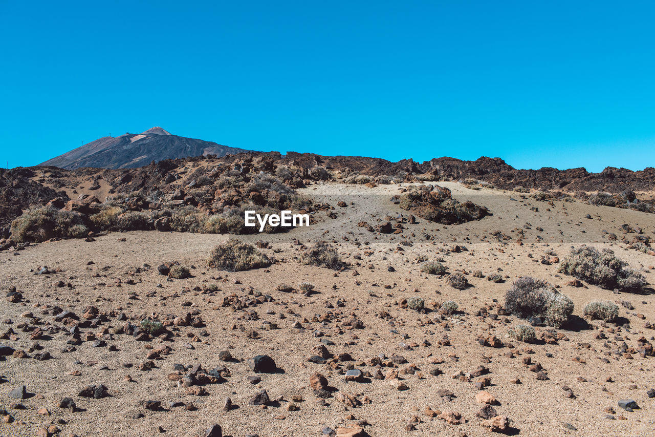 Scenic view of desert against clear blue sky