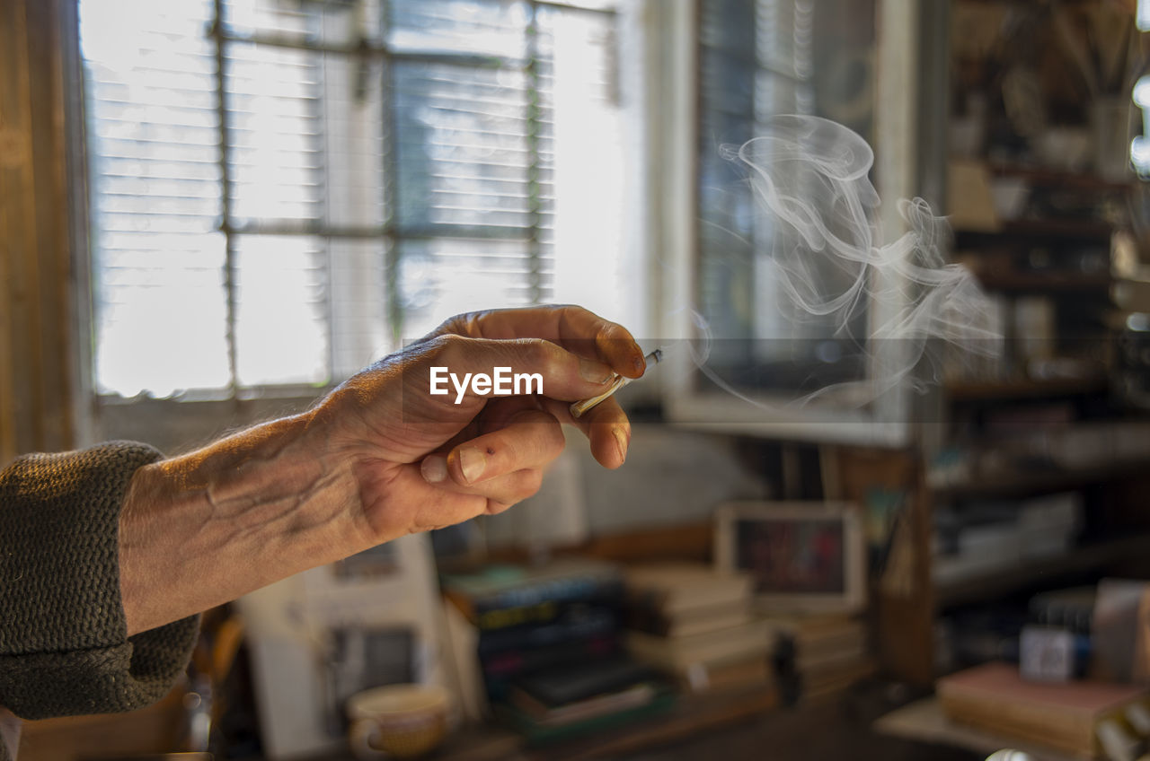 Cropped hand of an old man holding a cigarette