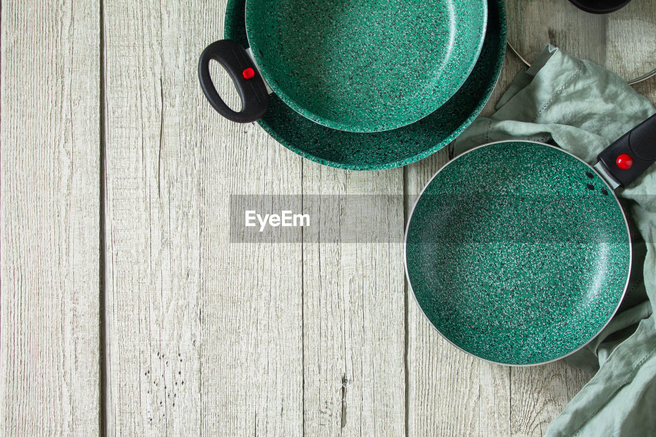 New set empty fry pan green with ceramic coatingon on a rustic kitchen table. top view. 