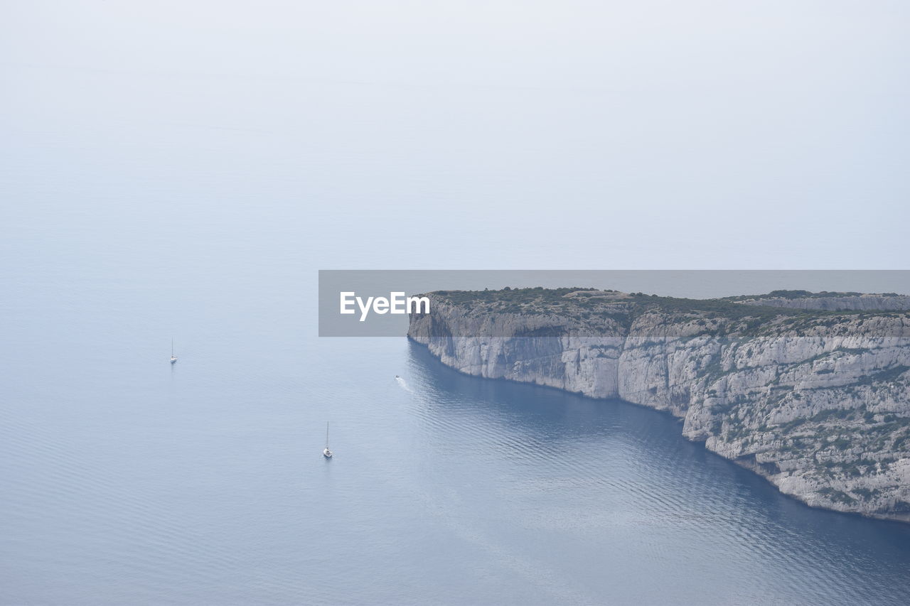 HIGH ANGLE VIEW OF SEA BY ROCKS AGAINST SKY