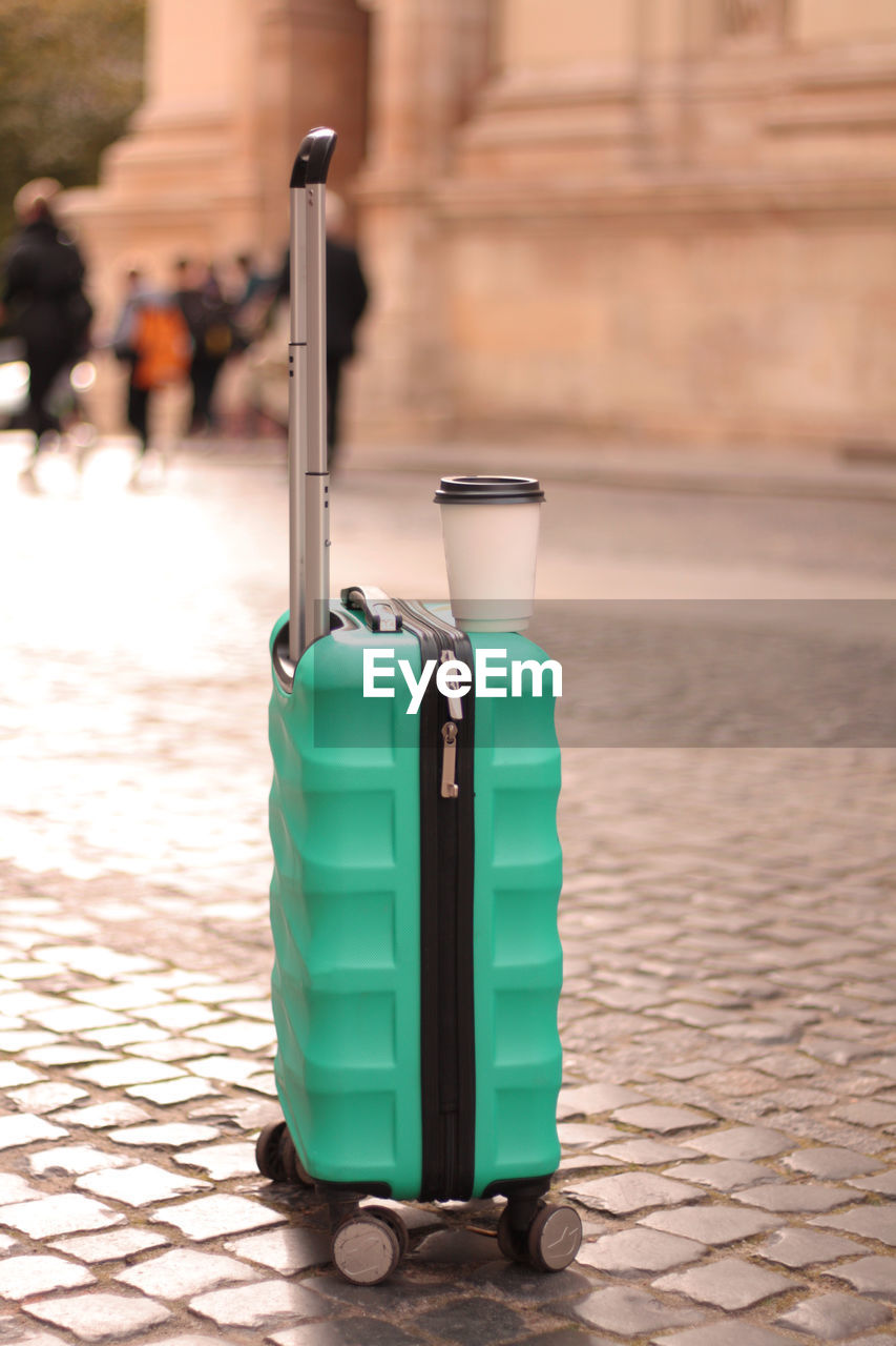 A suitcase with a cup of coffee dries up in the middle of the street