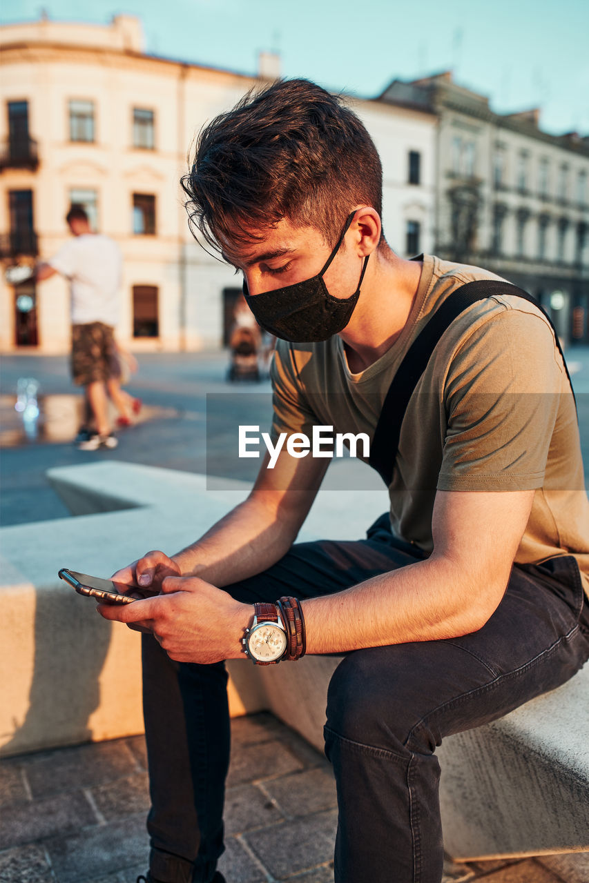 Young man using mobile phone in city