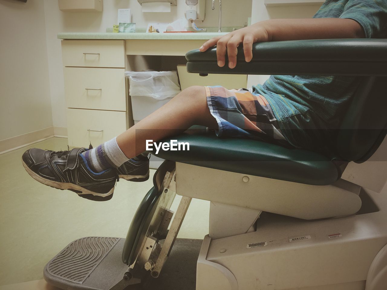 Low section of boy sitting on dentist chair