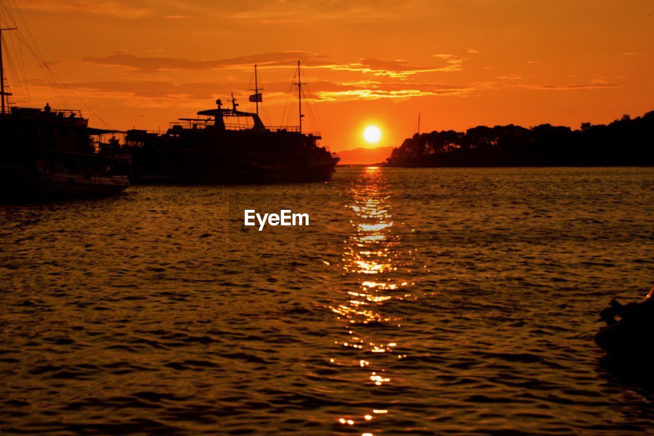 SILHOUETTE SAILBOAT ON SEA AGAINST ORANGE SKY