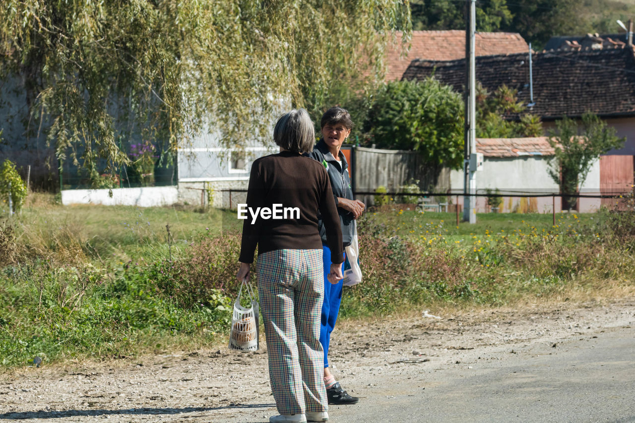 REAR VIEW OF COUPLE WALKING ON ROAD