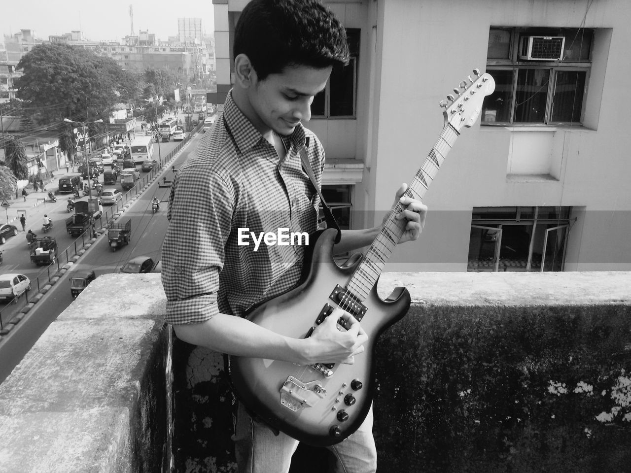 Young man playing guitar while standing on terrace