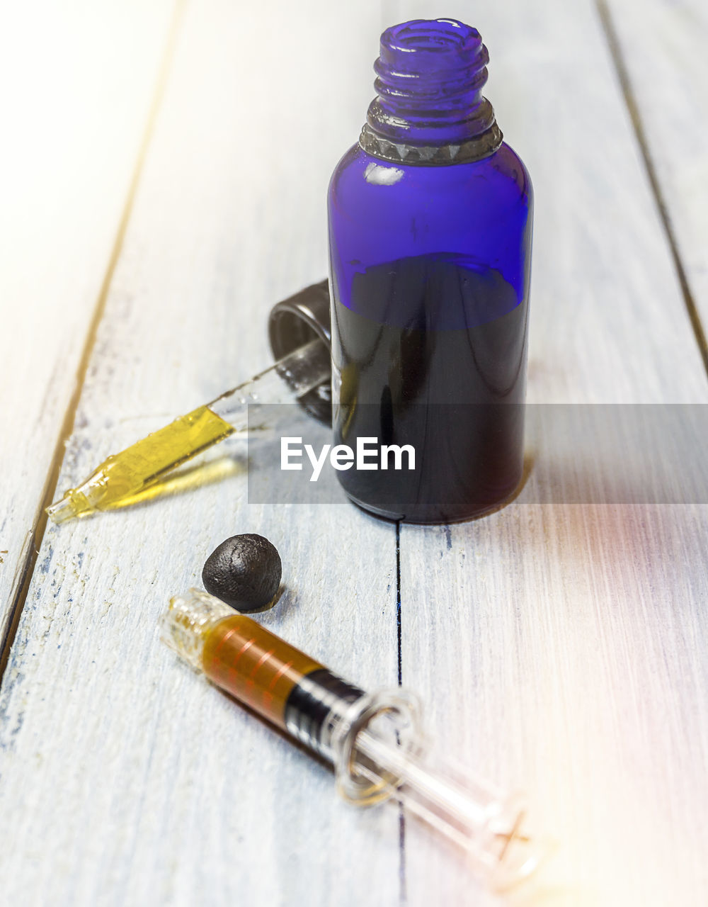 Close-up of syringe with medicine bottle on table