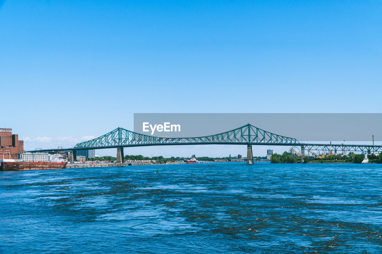 View of bridge over sea against clear blue sky