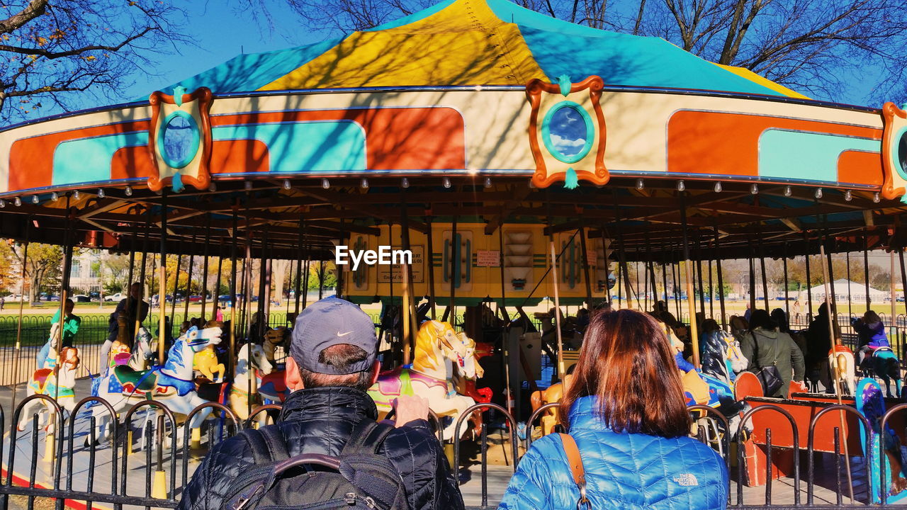 REAR VIEW OF PEOPLE ON AMUSEMENT PARK RIDE